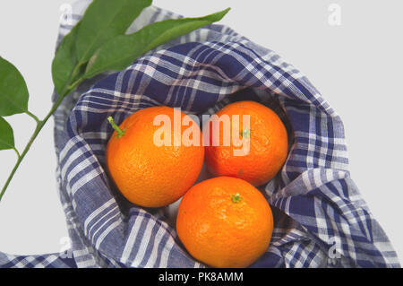 Three tangerines wrapped with a typical Valencian handkerchief accompanied by an orange branch with green leavesGroup of oranges decorated with orange Stock Photo