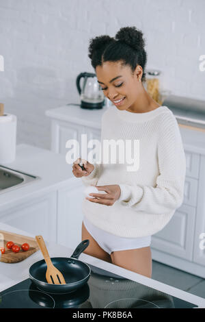 smiling young woman preparing scrambled egg for breakfast at kitchen Stock Photo