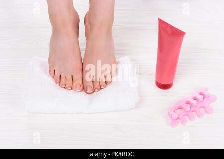 partial view of barefoot woman on towel near toe finger separators and cream container in beauty salon Stock Photo