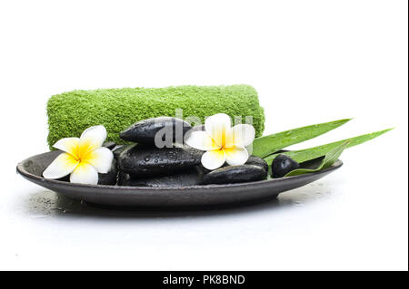 spa flower and black stones with green towel on dark plate Stock Photo