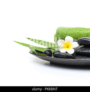 Tropical flower and black stones with green towel on dark plate Stock Photo