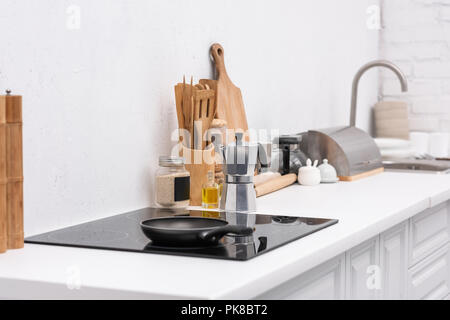frying pan on induction panel at modern kitchen with various utensils Stock Photo
