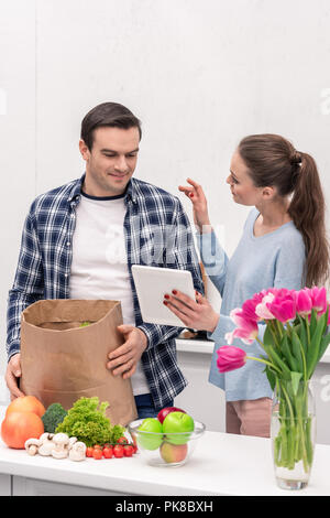 happy adult couple checking buys list in tablet after grocery shopping Stock Photo