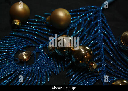 Sparkling blue feathers decoration and golden Christmas balls on dark background Stock Photo