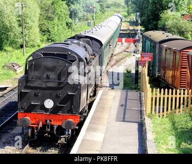 Corfe, England - June 03 2018: Steam engine pulling a passenger train, coming into Corfe Castle station, on the Swanage Railway in Dorset Stock Photo