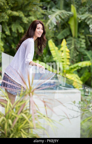 Happy young Chinese woman relaxing on balcony Stock Photo