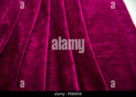 Red velvet fabric folded in an accordion, lies on the table top view Stock Photo