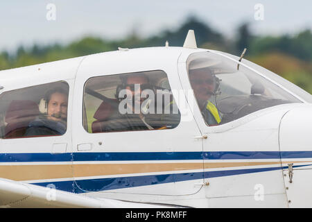Small group of people sitting in a single engine private aircraft looking out the window smiling, ready to take off, in the UK. Private pilot. Stock Photo