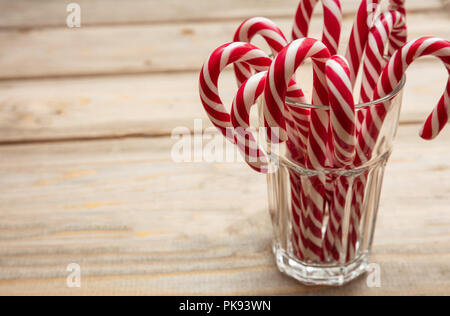 Christmas time. Candy canes in a glass, wooden background, copy space Stock Photo