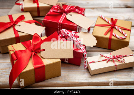 Christmas gift boxes with red ribbons and blank tags on wooden background Stock Photo