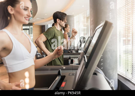 Group of four people running on treadmills in fitness gym Stock Photo