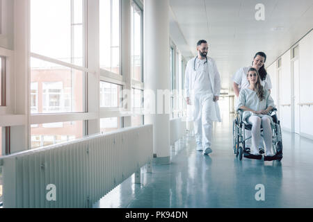 Doctor, nurse, and patient in wheelchair on hospital corridor Stock Photo