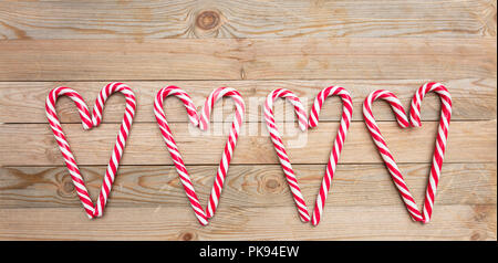 Christmas time. Candy canes heart shaped on wooden background Stock Photo