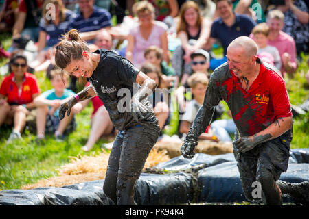 A man in a mud wrestling pit at the Lowland Games  chases a woman to make her more muddy Stock Photo