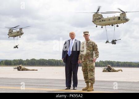 President Donald J. Trump and Maj. Gen. Walter E. Piatt, commander of the 10th Mountain Division (LI), look on as CH-47 Chinook helicopters carry in artillery during a demonstration at Fort Drum, New York, on August 13, August 13, 2018. The demonstration was part of President Donald J. Trump's visit to the 10th Mountain Division (LI) to sign the National Defense Authorization Act of 2019, which increases the Army's authorized active-duty end strength by 4, 000 enabling us to field critical capabilities in support of the National Defense Strategy. (U.S. Army photo by Sgt. Thomas Scaggs) -A-TZ47 Stock Photo