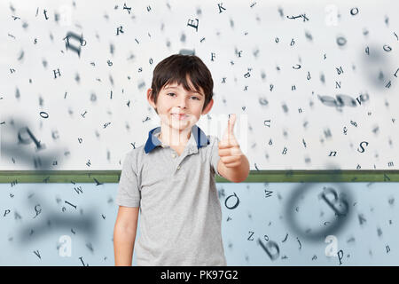 Pupils in elementary school holding thumbs up in front of a whiteboard with many flying letters Stock Photo