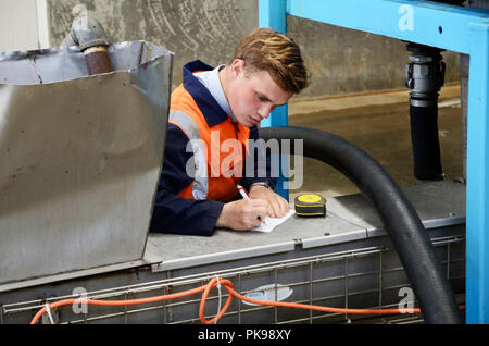 an engineer measures and plans a modification to a machine at a rendering factory that makes meat meal from offal. Stock Photo