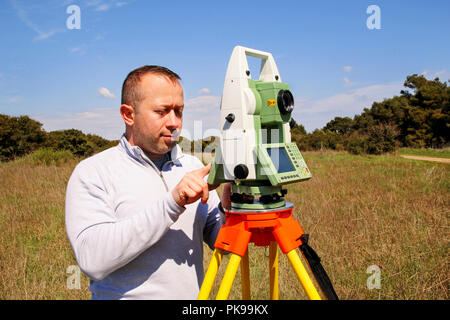 Man using of total station. Guy surveyor at work. Survey Instrument geodetic device, total station set and surveyor worker making measurement. Stock Photo