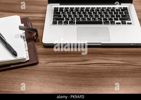 Office desktop. On the desk is a laptop, an empty notebook and a ballpoint pen. Stock Photo