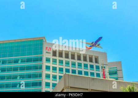 San Jose, CA, United States - August 12, 2018: Adobe headquarters skyscraper in Silicon Valley, with an airplane flying above from the close international airport Norman Y. Mineta of San Jose. Stock Photo