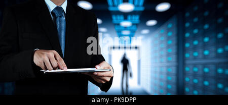 Businessman working with VR wide blank screen computer on server room in background. Stock Photo