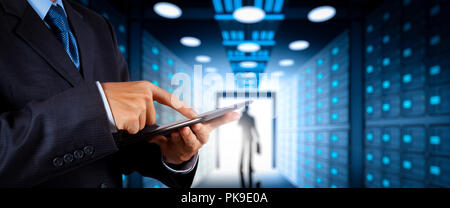 Businessman working with VR wide blank screen computer on server room in background. Stock Photo