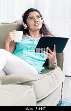 Thoughtful young woman holding coffee cup and digital tablet Stock Photo