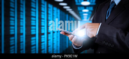 Businessman working with VR wide blank screen computer on server room in background. Stock Photo