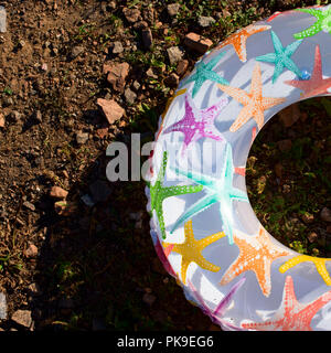 Bright children's inflatable circle lying on the ground on the beach. Lifeline is white with a picture of a starfish Stock Photo