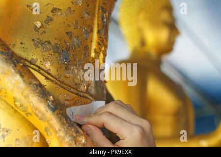 Buddhists make merit,Gilding gold leaf to Buddha for worship. ,Buddhist culture for happy life.  Selective focus. Stock Photo