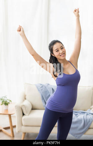 Cheerful pregnant woman practicing yoga at home Stock Photo