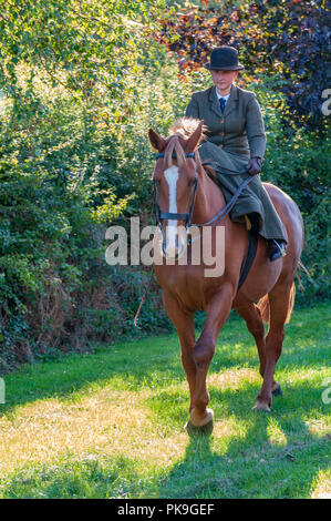 An elegent young lady riding in a traditional side saddle wearing bowler hat and face veil Stock Photo