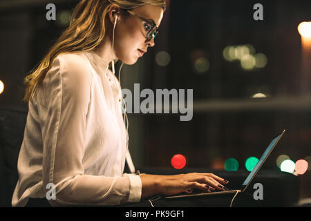 Young woman working late at office. Businesswoman using laptop in office lobby. Stock Photo