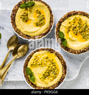 vegan raw mini tarts from nuts and dates with cashew cream from mango purée with lime juice and seeds of passion fruit. healthy alternative food on a 