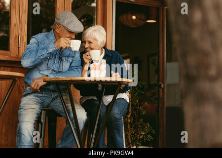 Happy senior couple sitting at coffee shop and talking. Elderly man and woman relaxing at cafe and having coffee. Stock Photo