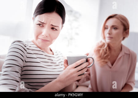 Unhappy woman turning her head while crying and drinking tea Stock Photo