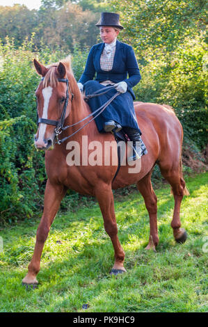 An elegent young lady riding in a traditional side saddle wearing top hat and face veil Stock Photo