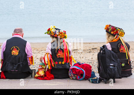 Phoenix Morris dancers sitting at the beach at Swanage Folk Festival, Dorset UK on a lovely warm sunny day in September Stock Photo