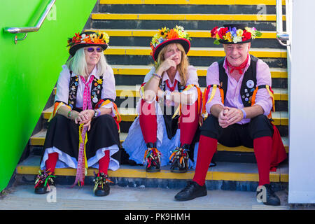 Phoenix Morris dancers sitting on steps at Swanage Folk Festival, Dorset UK on a lovely warm sunny day in September Stock Photo