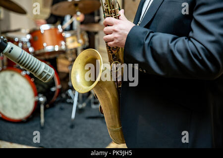 Musical entertainment on the concert with fiery atmosphere and bright lighting. saxophone with specks on it in male hands. Close up Stock Photo
