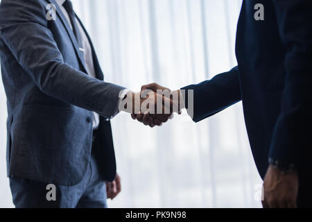 Close up of two businessmen handshaking after good deal. Business people shaking hands and finishing up a meeting in office. Stock Photo