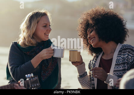 Female friends having coffee at the beach. Women with friends partying at beach and having coffee.