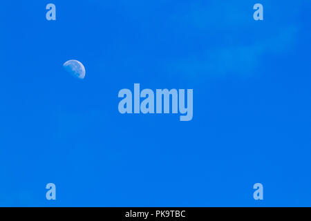Partial moon against a blue morning sky with haze and clouds Stock Photo
