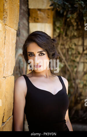Beautiful woman leaning against wall outdoors Stock Photo
