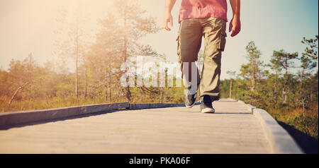 Man walking on wooden walkway in nature Stock Photo