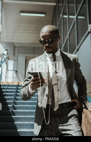 Stylish confident businessman using smartphone while walking on stairs Stock Photo
