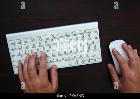 Man working at office desk with computer keyboard and mouse Stock Photo