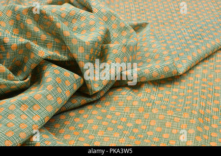 Silk fabric with cotton, smears of orange peas on a green cage Stock Photo