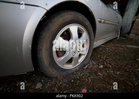 Popped tyre on a car (vauxhall car with deflated front tyre from puncture) Stock Photo