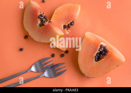 Papaya on orange background with forks. Healthy organic fruit is a perfect snack full of vitamins and antioxidants for a healthy lifestyle Stock Photo